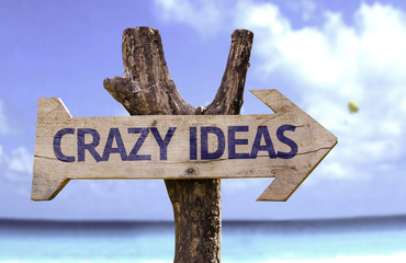 Crazy Ideas wooden sign with a beach on background