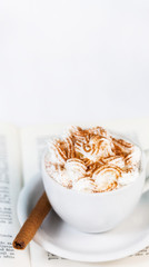 Cup of coffee with cream on open book.