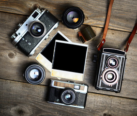 Vintage cameras with lenses and blank old photograph on wooden b