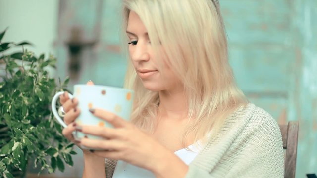 Beautiful, blonde young woman drinking tea in the garden