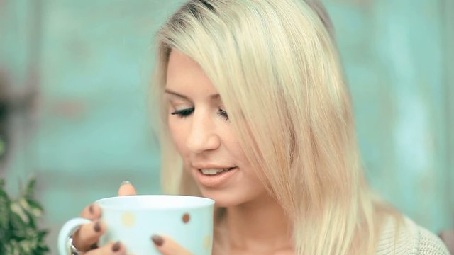 Beautiful, blonde young woman drinking tea in the garden