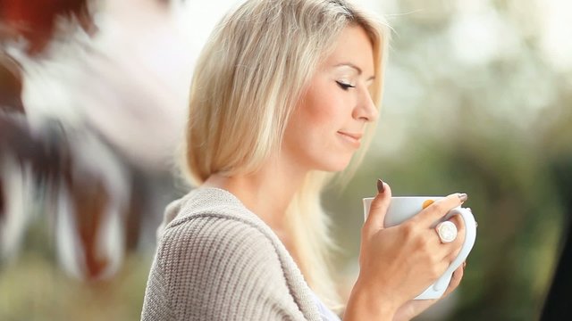 Beautiful, blonde young woman drinking tea in the garden