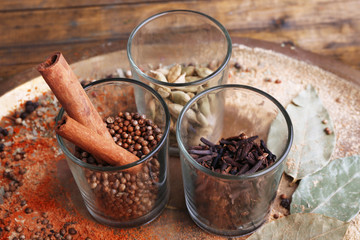 Round glasses of seasoning on wooden background