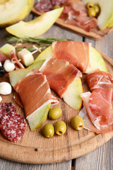 Delicious melon with prosciutto on table close-up