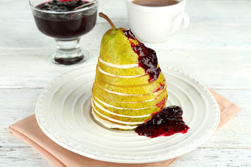 Tasty dessert with sliced pear, cream and berry sauce
