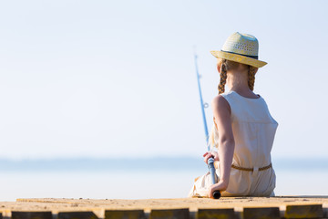 Girl in a dress and a hat with a fishing rod