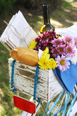 Bicycle with flowers, bread and bottle of wine in wooden box