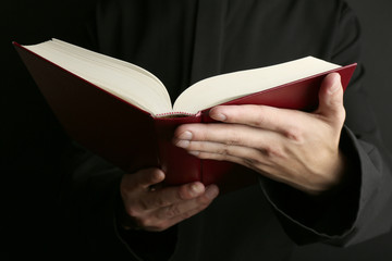 Man holding Bible on dark background
