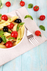 Pasta with tomatoes, olives and basil leaves in bowl