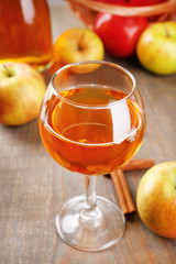 Apple cider in wine glass and bottle, with cinnamon sticks and