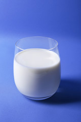 Milk in glass on blue background