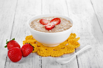 Tasty oatmeal with strawberry on table close-up