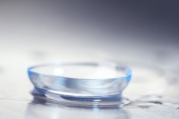Contact lens with water drops on bright background