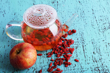 Goji berries drink in glass teapot and ripe apple