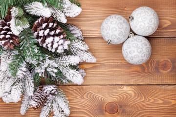 Fototapeta na wymiar Christmas fir tree with snow and baubles on rustic wooden board