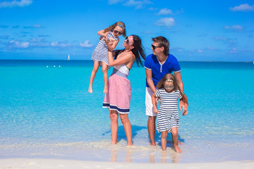 Young family of four at tropical white beach