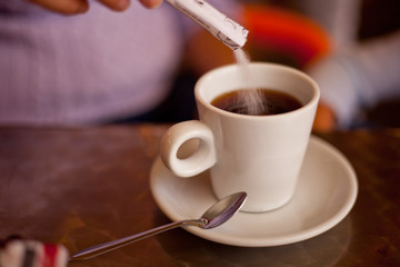 Sugar falling in cup filled with tea