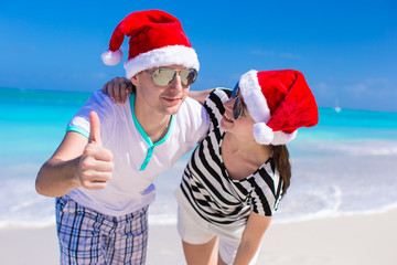 Young romantic couple in Santa hats during beach vacation
