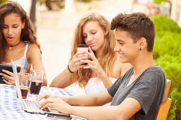 Teenage Friends Sitting At Caf‚ Using Digital Devices