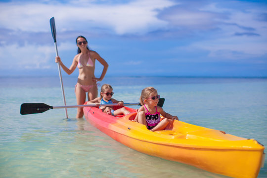 Young mother and two her little daughters kayaking at tropical