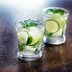 two mojito cocktails on wet wooden table