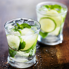 two ice cold fresh mojito cocktails on wooden table