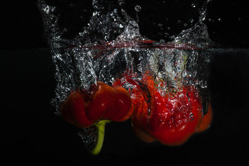 Rote Paprika Splashes mit schwarzem Hintergrund