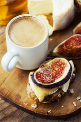Breakfast setting with coffee, bread, cheese, figs and honey