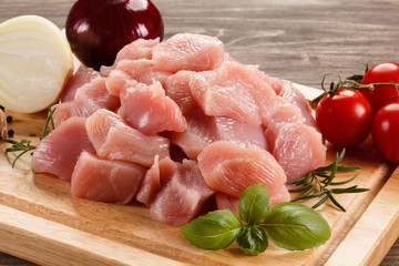 Raw turkey meat on cutting board on wooden background