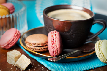 Cup of coffee and macaroons on wooden table, toned