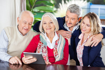 Senior Woman Using Digital Tablet With Family At Nursing Home