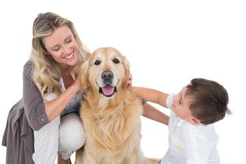 Smiling mother and son petting their golden retriever