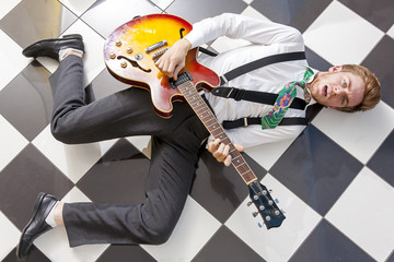 fifties style - young guitarist playing lying on the floor