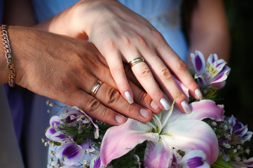 Fototapeta premium two hands with wedding rings and flowers