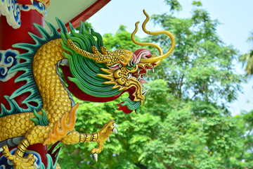 Fototapeta na wymiar Statue of a dragon wrapped around a pole building.