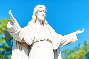 Statue of Jesus Christ opening his arms on a blue sky