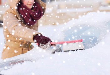 closeup of woman cleaning snow from car
