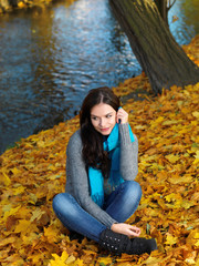 Woman in Autumn Outfit Sitting on Dry Leaves