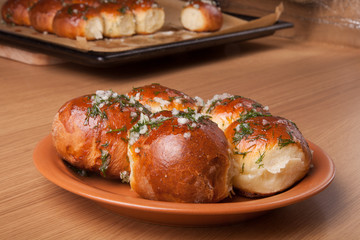 freshly baked rolls lying in the ceramic dish on wooden table
