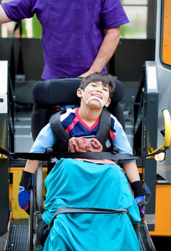 Disabled boy riding on school bus lift