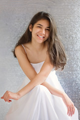 Fototapeta na wymiar Beautiful biracial teen girl in white dress, sitting arms crosse