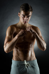 young man on fighting stand over black background