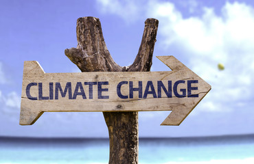Climate Change wooden sign with a beach on background