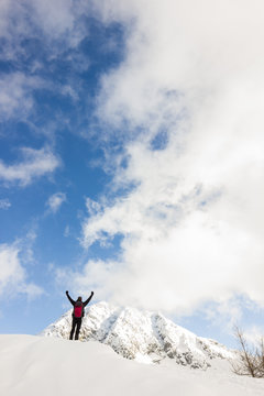Uomo con braccia in alto in montagna d'inverno con ciaspole