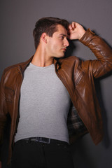 Man posing in leather jacket near wall