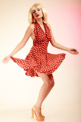 Pinup girl in blond wig retro dress dancing