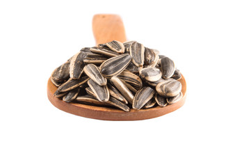 Sunflower seeds on wooden spoons over white background