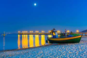 Obraz premium Baltic beach with fishing boat at night, Poland