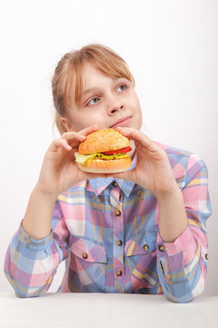 Little blond girl with homemade hamburger on white background