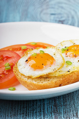 Fried quail eggs with a toast and tomatoes
